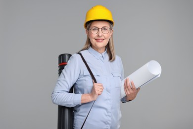 Photo of Architect in hard hat with draft and tube on grey background