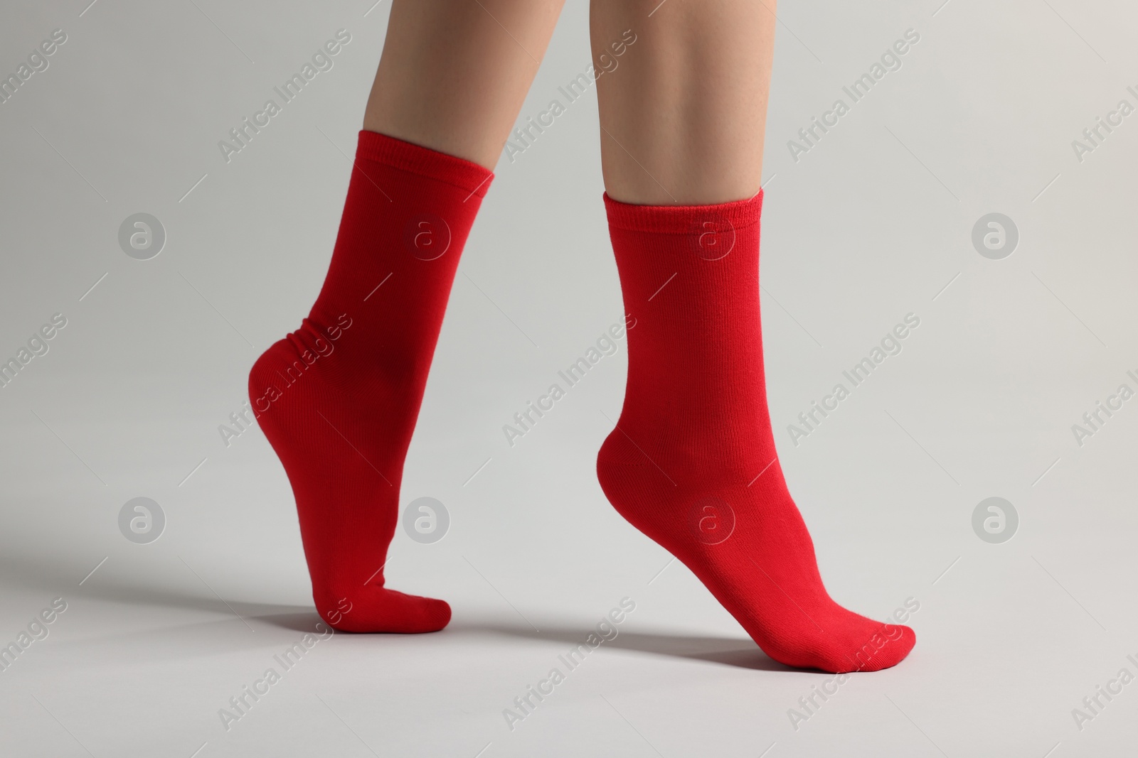 Photo of Woman in stylish red socks on light grey background, closeup