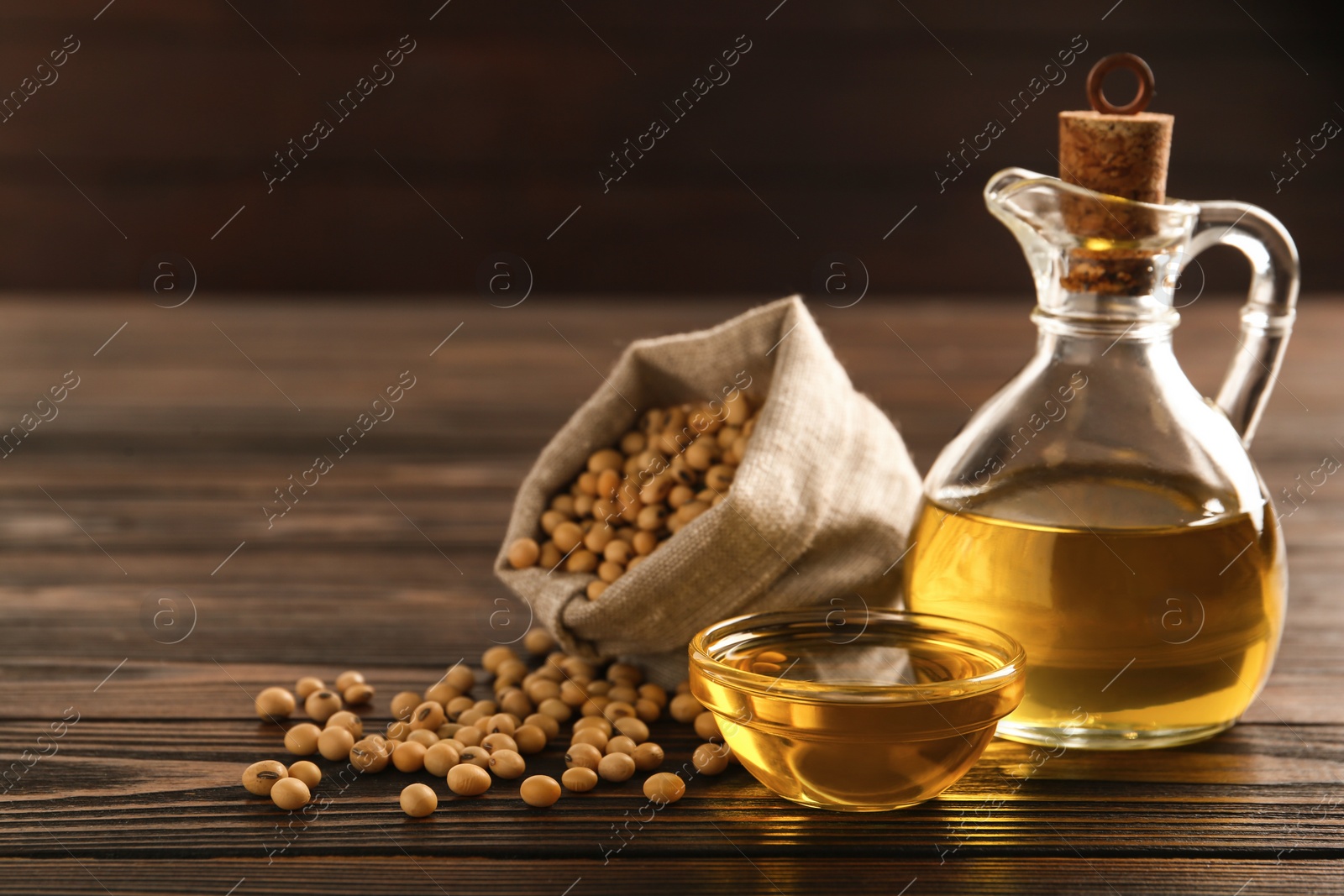 Photo of Composition with soybean oil on wooden table, space for text