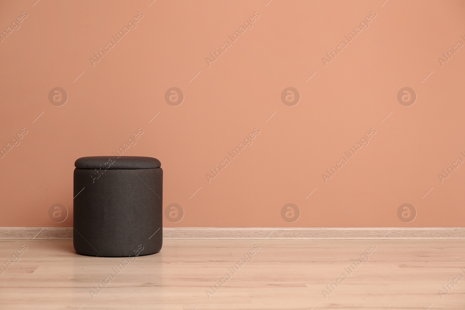 Photo of Comfortable pouf near pale pink wall indoors, space for text