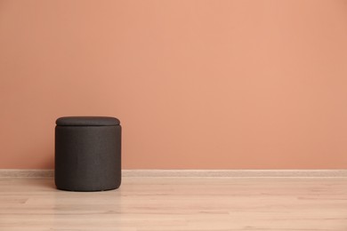 Photo of Comfortable pouf near pale pink wall indoors, space for text