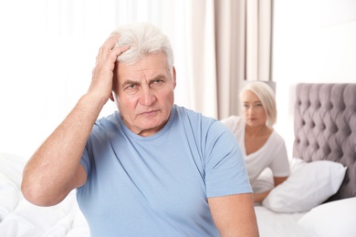 Mature couple with relationship problems ignoring each other in bedroom