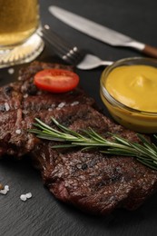 Photo of Delicious fried steak with rosemary and sauce on black table, closeup