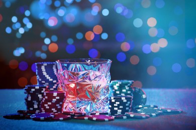 Image of Alcohol drink and casino chips on table against blurred lights. Bokeh effect