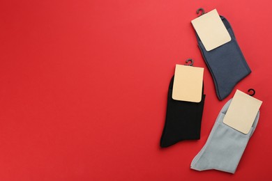 Photo of Soft cotton socks on red background, flat lay. Space for text