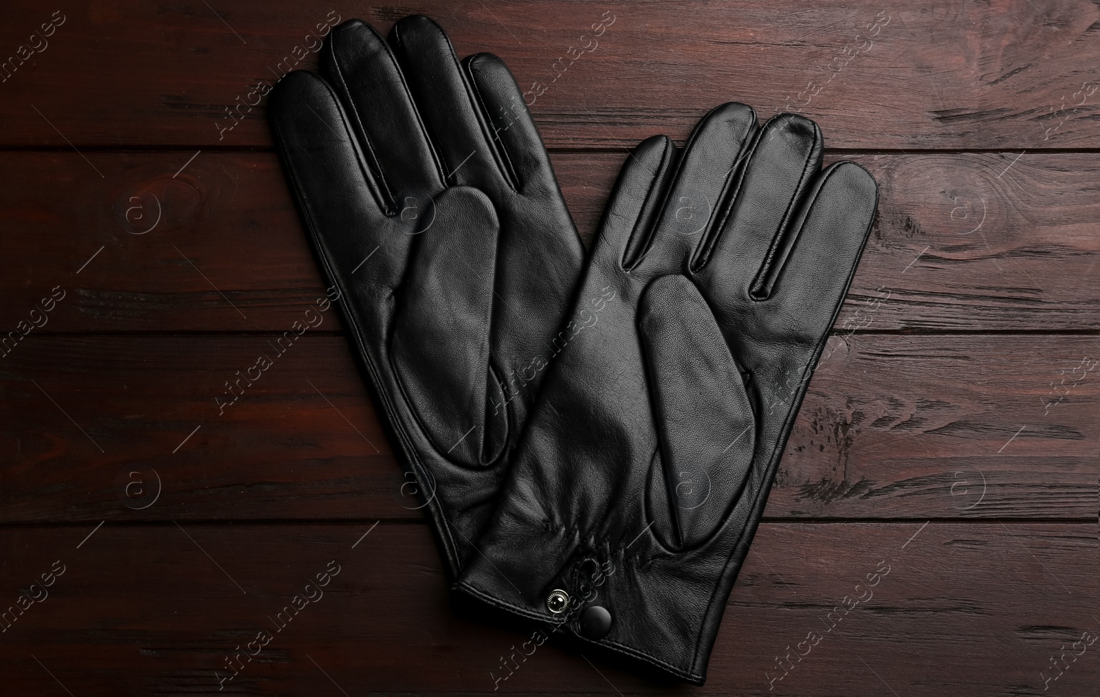 Photo of Stylish black leather gloves on wooden background, flat lay