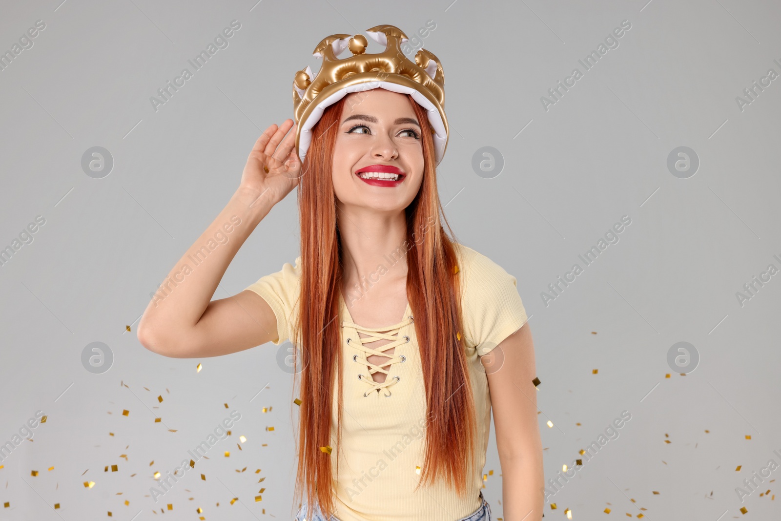 Photo of Beautiful young woman with inflatable crown on light grey background