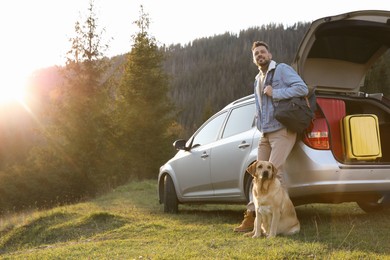 Photo of Happy man and adorable dog near car in mountains. Traveling with pet