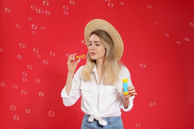 Young woman blowing soap bubbles on red background