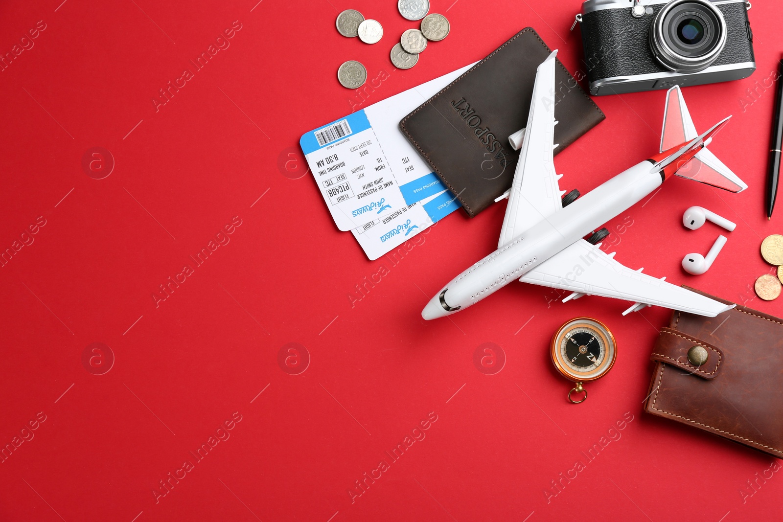 Photo of Flat lay composition with toy airplane and travel items on red background. Space for text