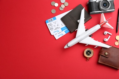 Photo of Flat lay composition with toy airplane and travel items on red background. Space for text