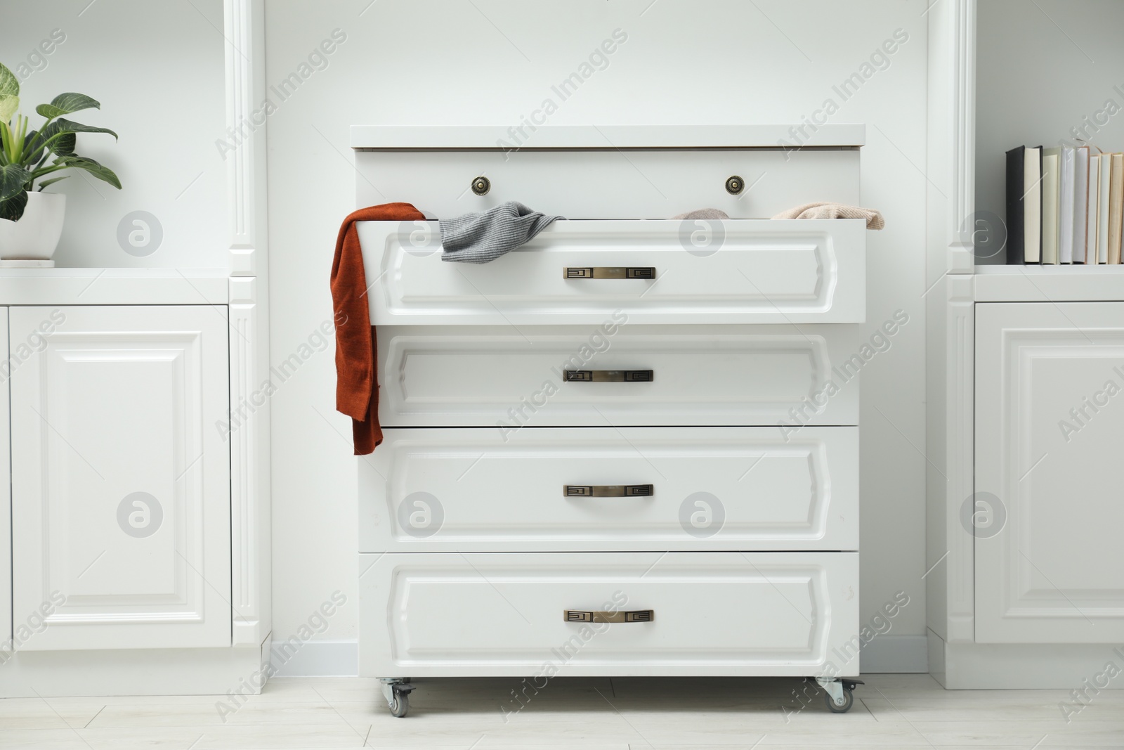 Photo of Cluttered chest of drawers indoors. Clothes in mess