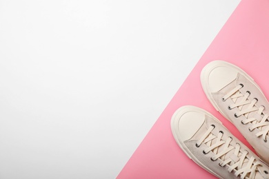 Pair of sneakers on color background, top view