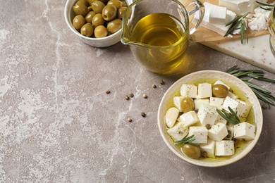 Flat lay composition with pickled feta cheese in bowl on light brown table. Space for text