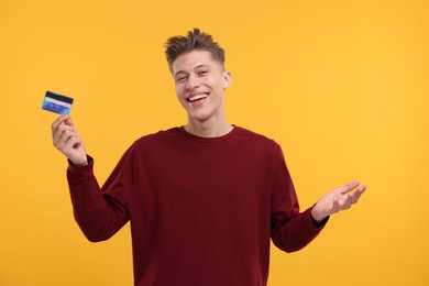 Photo of Happy man with credit card on yellow background