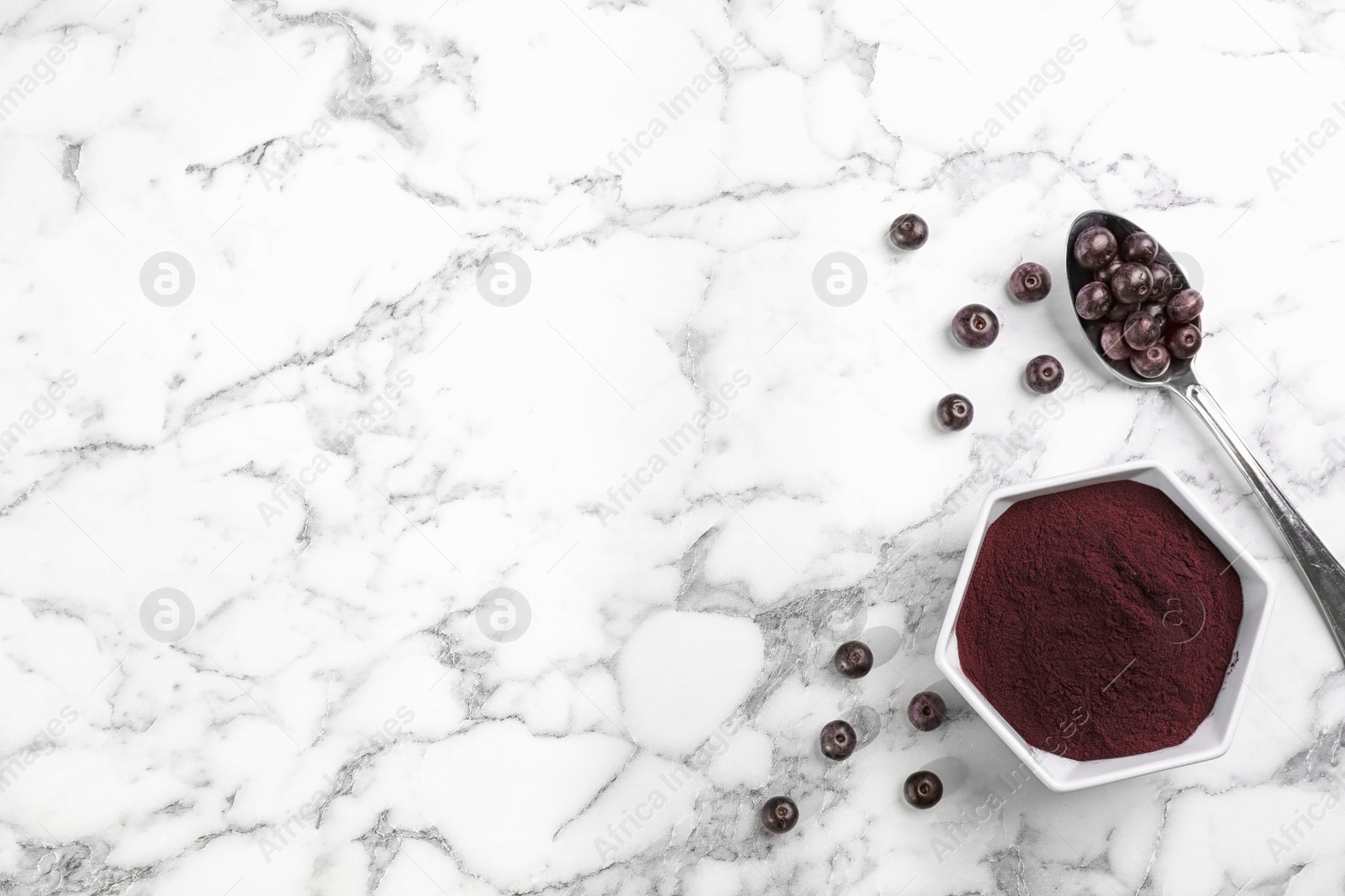 Photo of Bowl of acai powder and fresh berries on marble table, flat lay with space for text