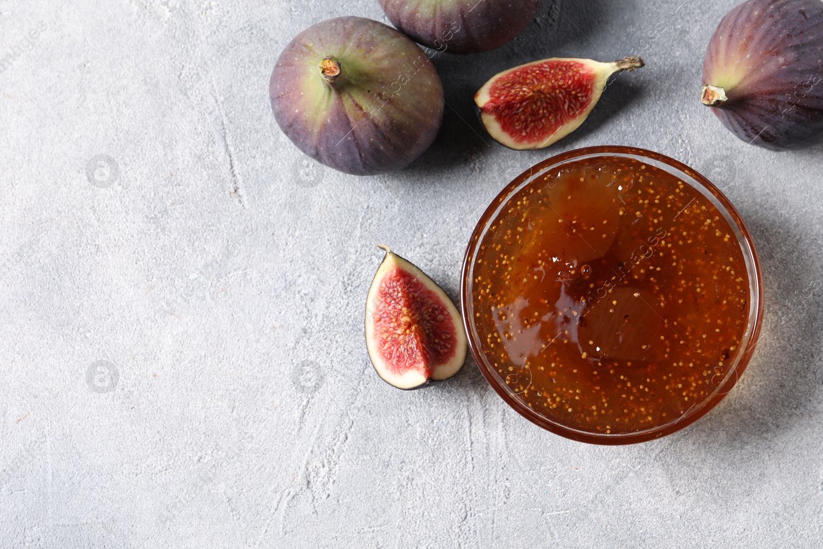 Photo of Glass bowl of tasty sweet jam and fresh figs on light table, flat lay. Space for text
