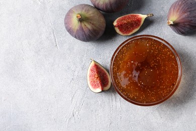 Glass bowl of tasty sweet jam and fresh figs on light table, flat lay. Space for text