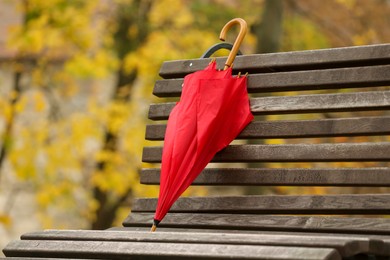 Photo of Red umbrella on bench in autumn park