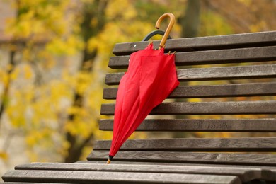 Red umbrella on bench in autumn park