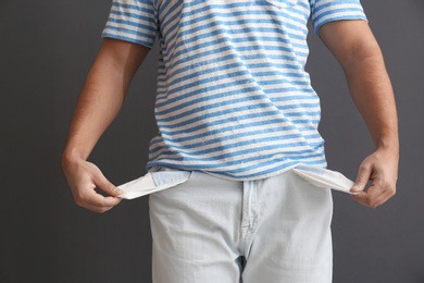Photo of Man showing empty pockets on grey background, closeup