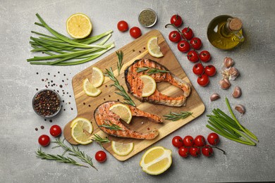 Photo of Tasty grilled salmon steaks and different ingredients on light grey table, flat lay