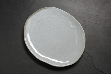 One ceramic plate on black textured table, top view