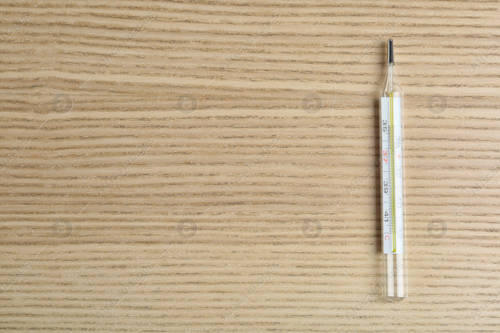 Photo of Mercury thermometer on wooden table, top view. Space for text