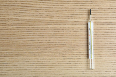 Mercury thermometer on wooden table, top view. Space for text