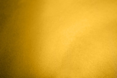 Photo of Blurred view of plain golden surface as background