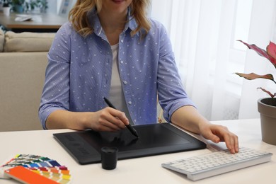 Professional designer with graphic tablet at table indoors, closeup