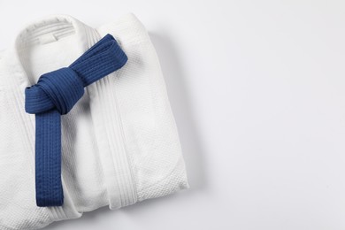 Blue karate belt and kimono on white background, top view. Space for text