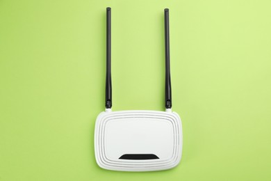 Photo of Modern Wi-Fi router on green background, top view