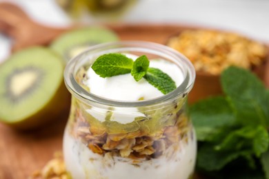 Photo of Delicious dessert with kiwi, yogurt and muesli in glass jar, closeup