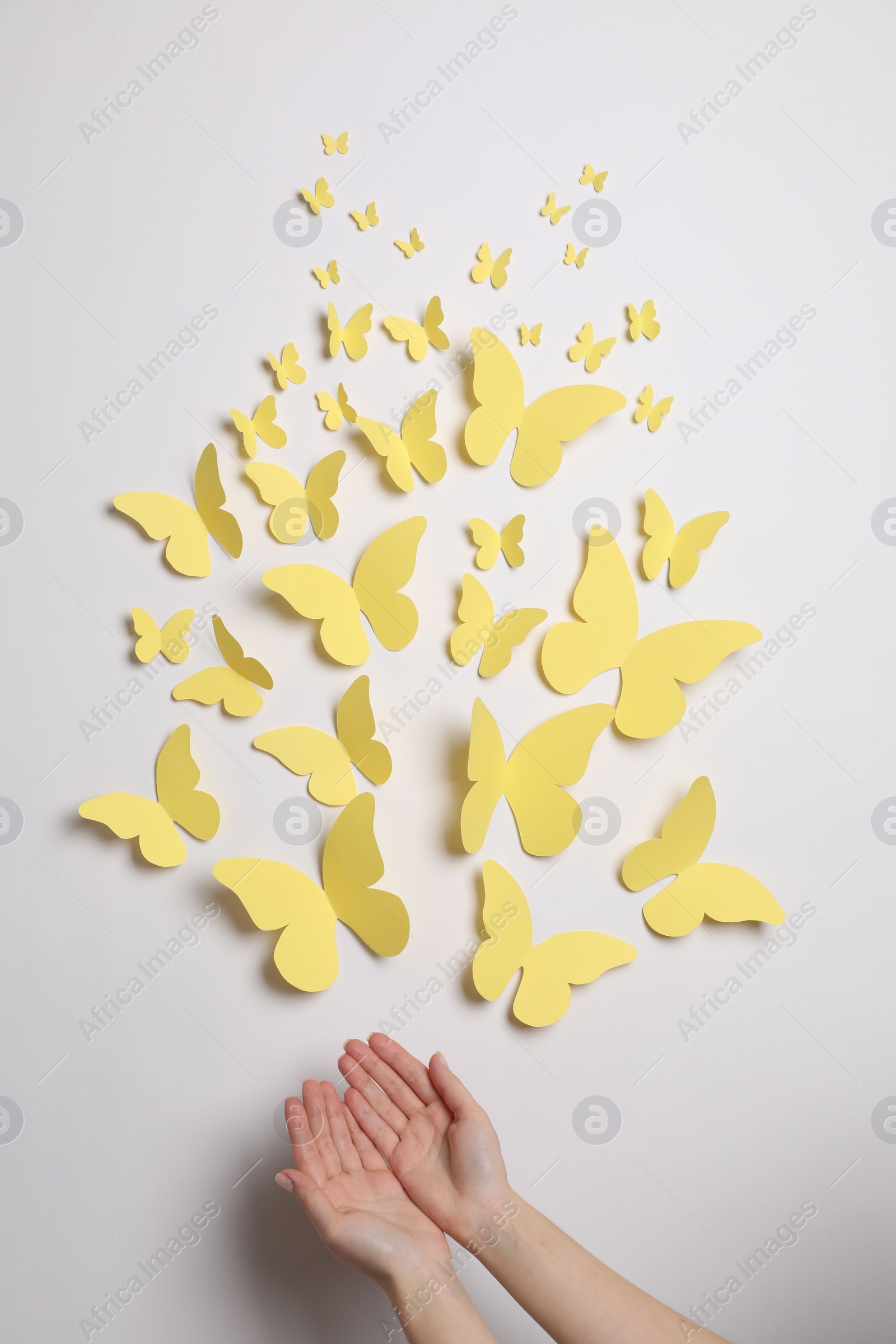 Photo of Woman with yellow paper butterflies on white background, top view