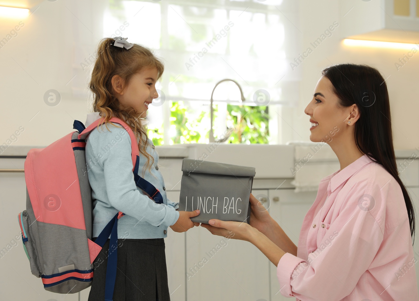 Photo of Young mother helping her little child get ready for school in kitchen