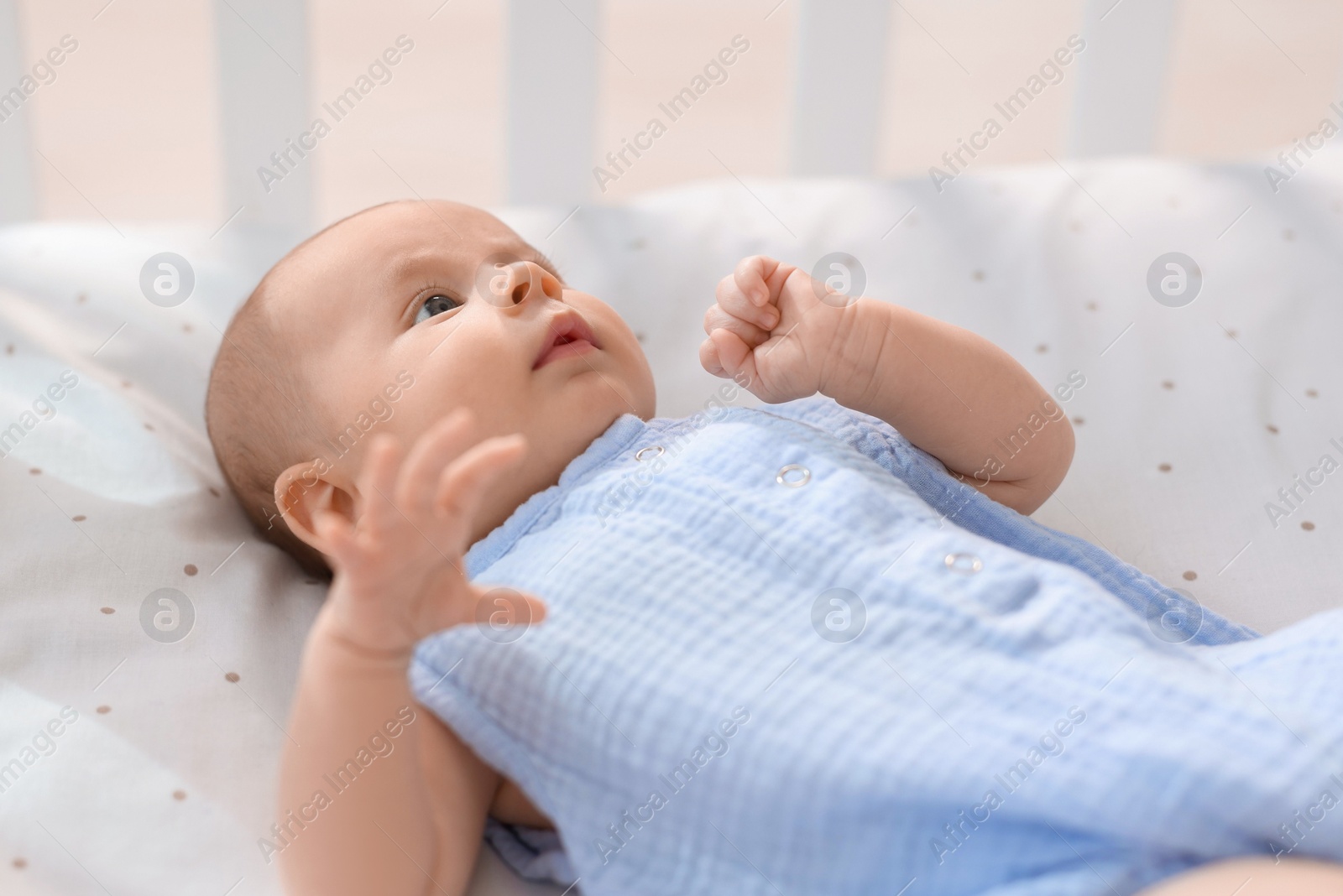 Photo of Cute little baby lying in crib at home