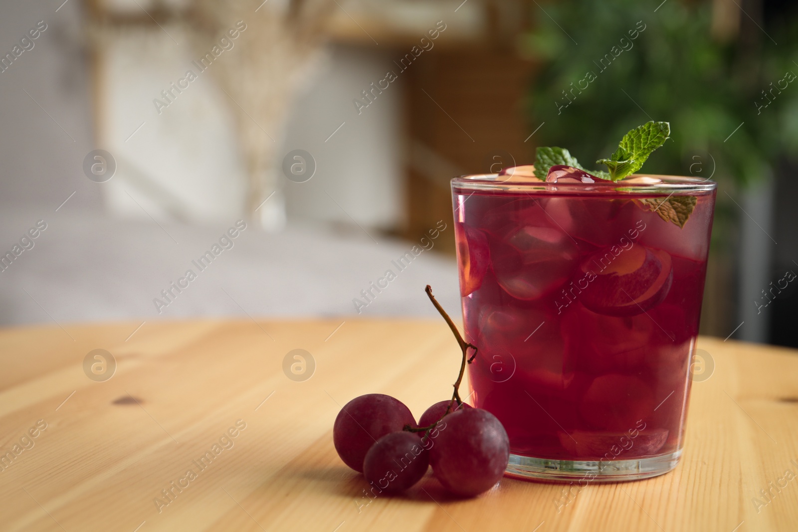 Photo of Refreshing drink with soda water, grapes, ice and mint on wooden table indoors. Space for text