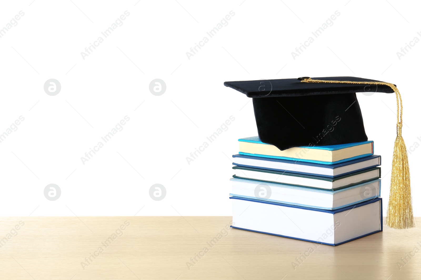 Photo of Graduation hat with books on table against white background