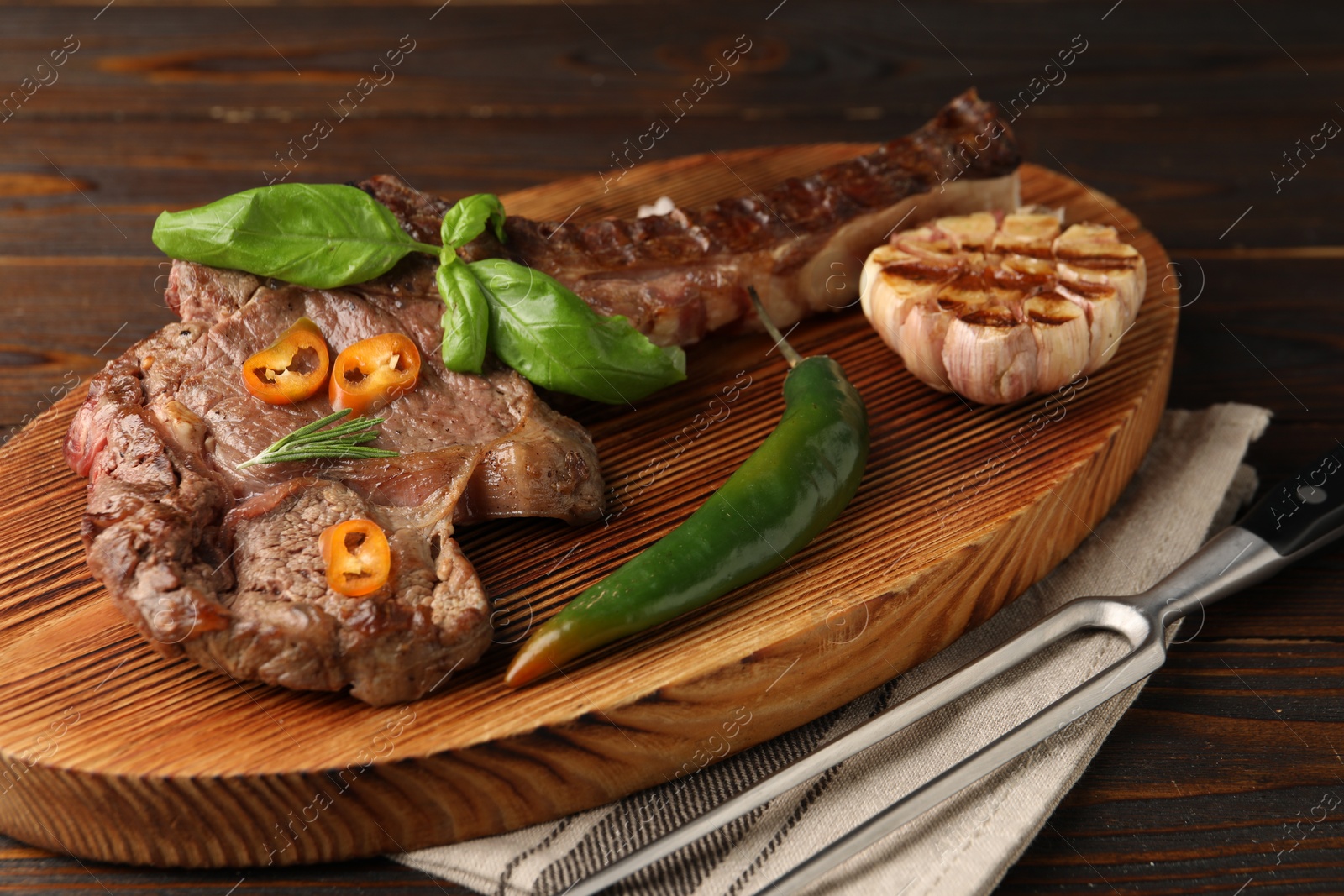 Photo of Delicious fried beef meat with garlic and chili pepper on table