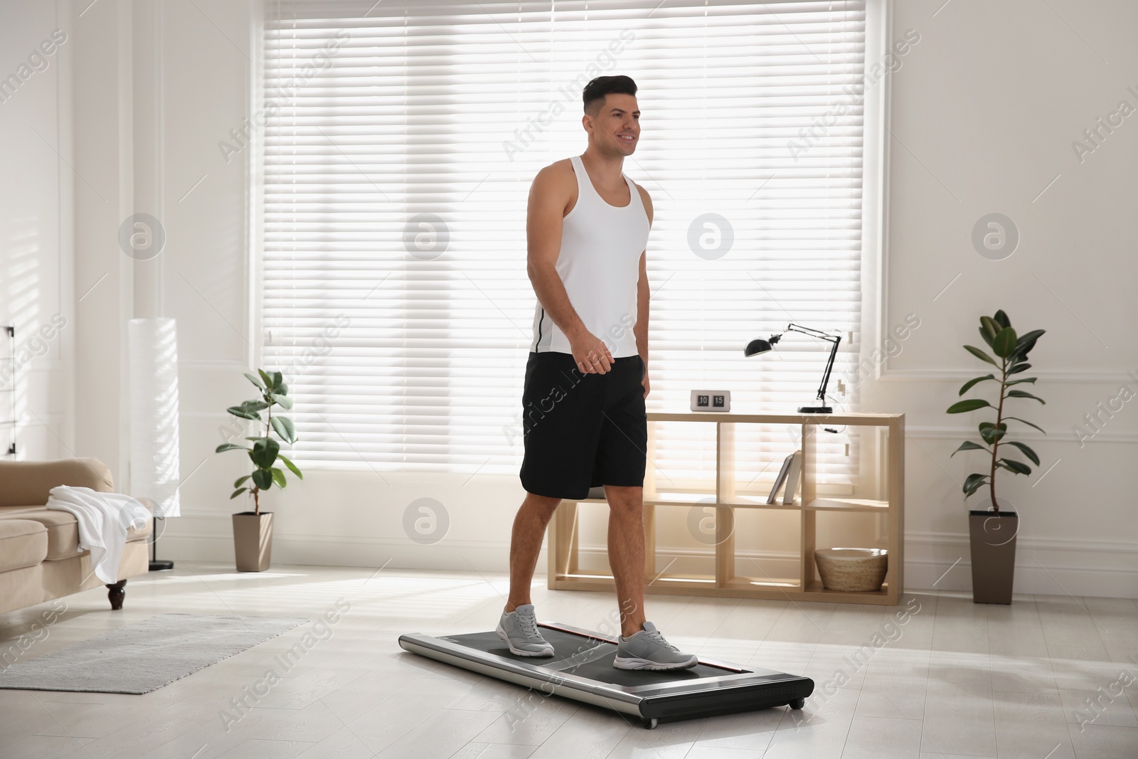 Photo of Sporty man training on walking treadmill at home