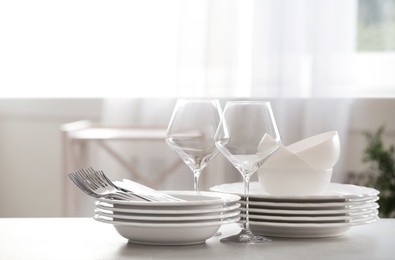 Photo of Set of clean dishware, cutlery and wineglasses on table indoors