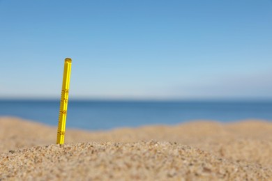 Photo of Weather thermometer in sand near sea, space for text