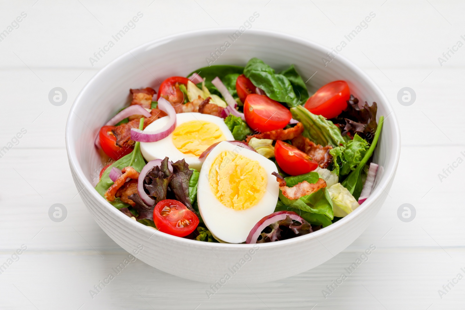 Photo of Delicious salad with boiled egg, bacon and vegetables on white wooden table, closeup