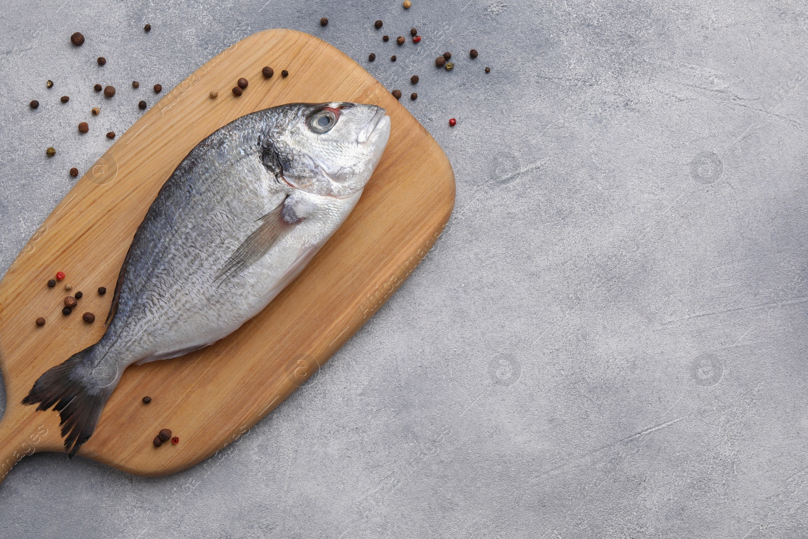 Photo of Fresh dorado fish and peppercorns on light gray table, flat lay. Space for text