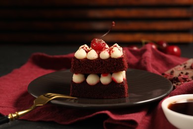 Photo of Piece of red velvet cake and fork on table, closeup