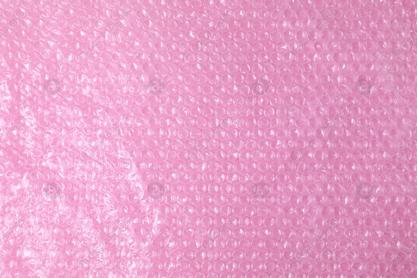 Photo of Transparent bubble wrap on pink background, top view