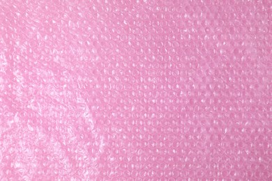 Photo of Transparent bubble wrap on pink background, top view