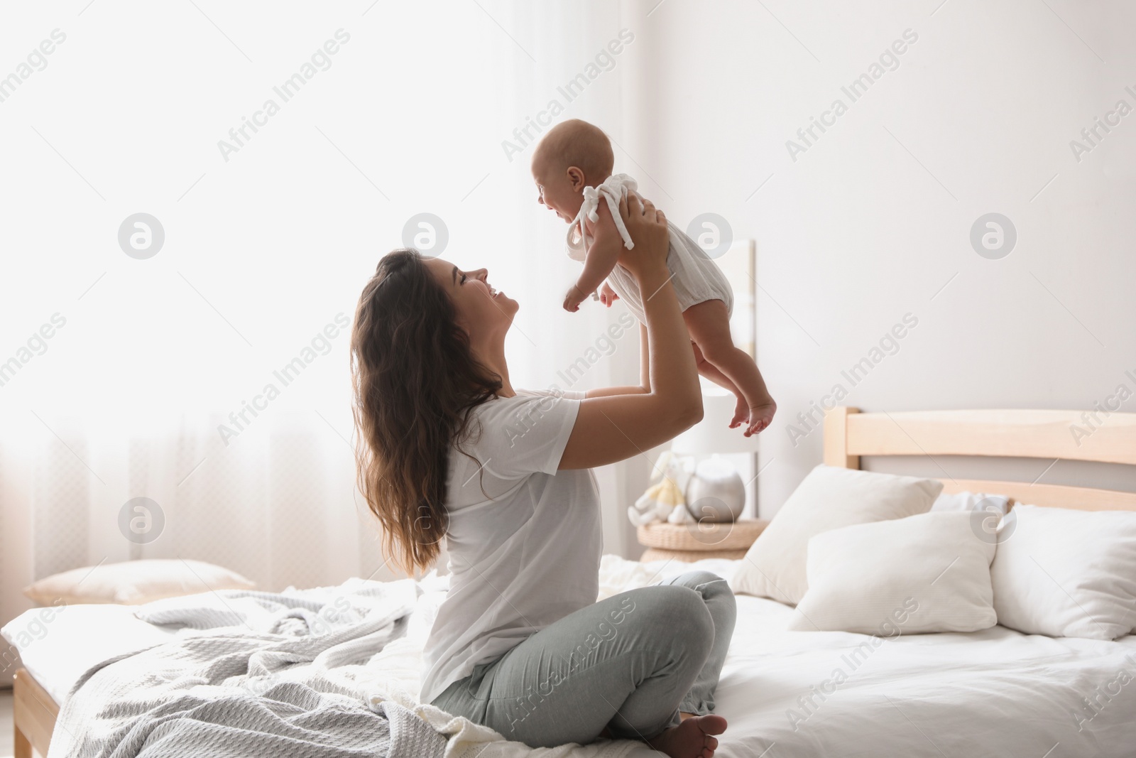 Photo of Happy young mother with her cute baby on bed at home