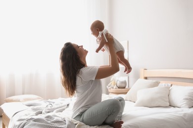 Photo of Happy young mother with her cute baby on bed at home